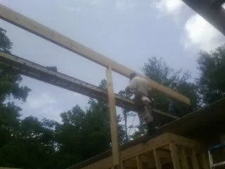 Carpenter setting a ridge beam over a new addition frame — Ice Dam Removal by Roofing Brothers in Goochland