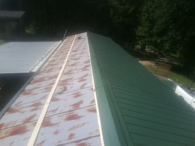 Old rusted panels beside newly installed green metal roofing — Wind Damage Roof Repair by Roofing Brothers in Goochland