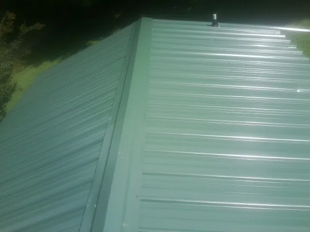 New green metal panels meeting at the ridge of a roof — Flat Roof Repair work by our crew in Goochland