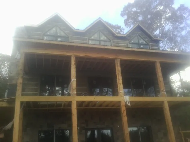 Dormers and porch framing on a large log home under construction — Roof Coating work by our crew in Goochland