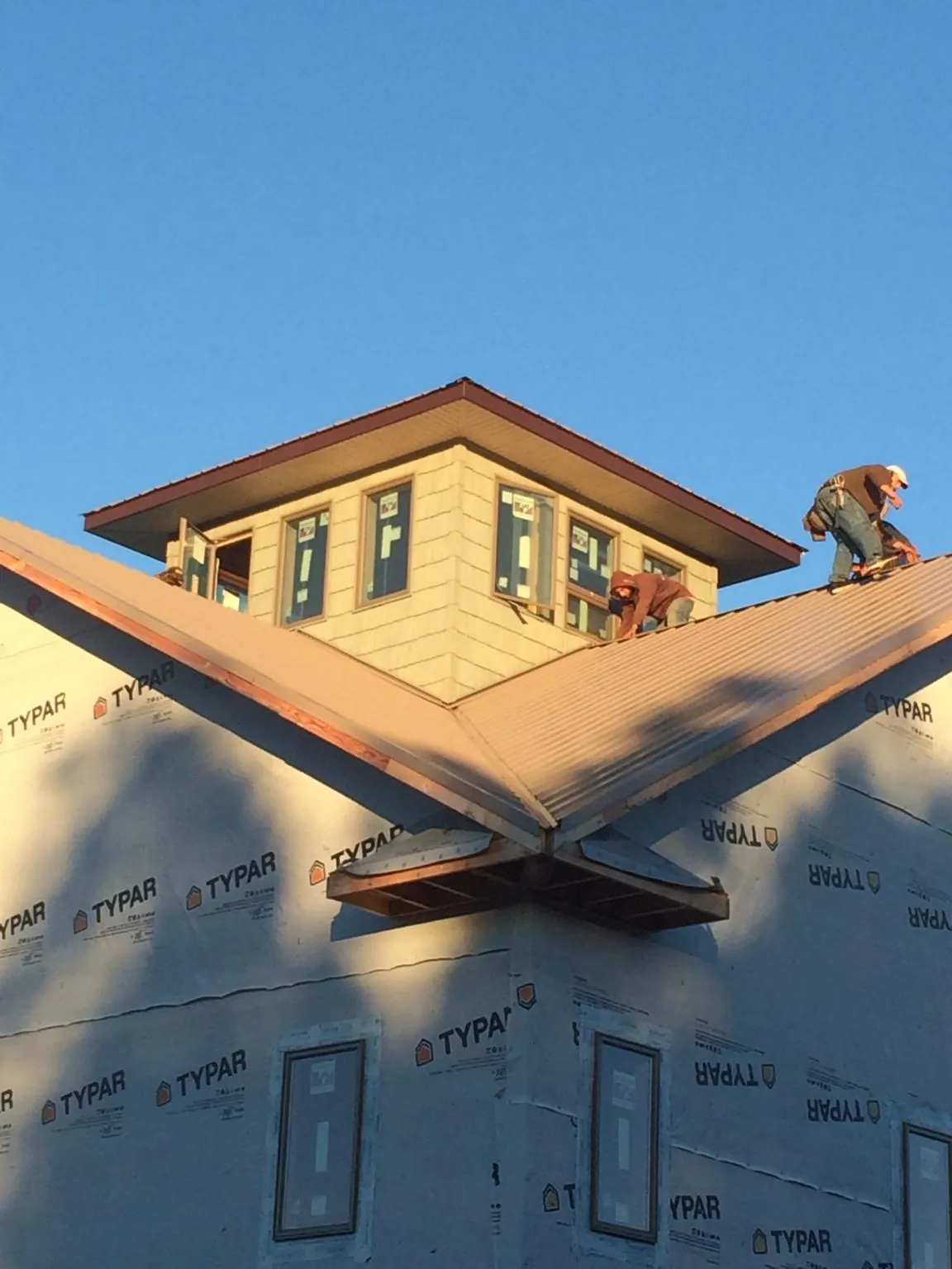 Roofers working around a rooftop cupola on a new metal roof at sunset — Roof Waterproofing in Goochland by Roofing Brothers